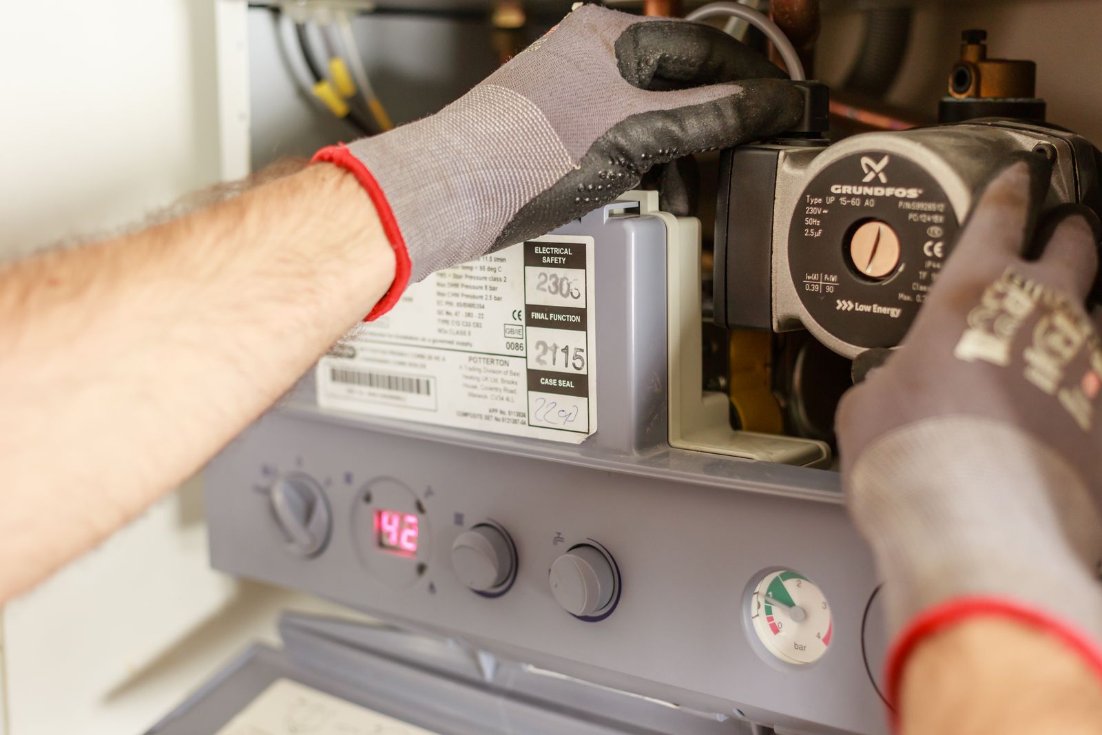 Tecnico che regola i comandi e il display di una caldaia a gas